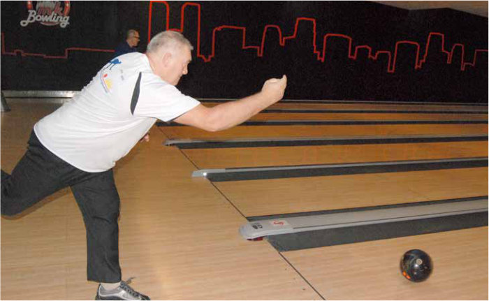 Mężczyzna rzucający bilą na torze bowlingowym