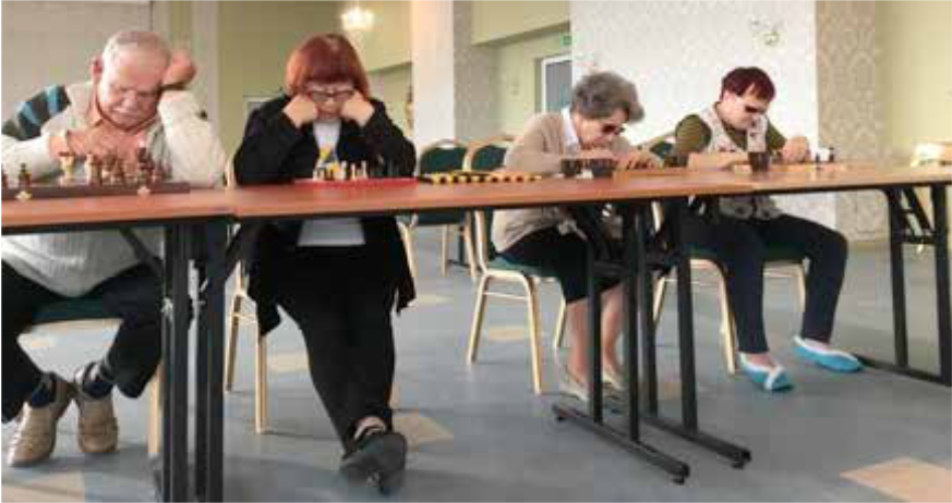 Osoby siedzące przy stolikach z szachownicami