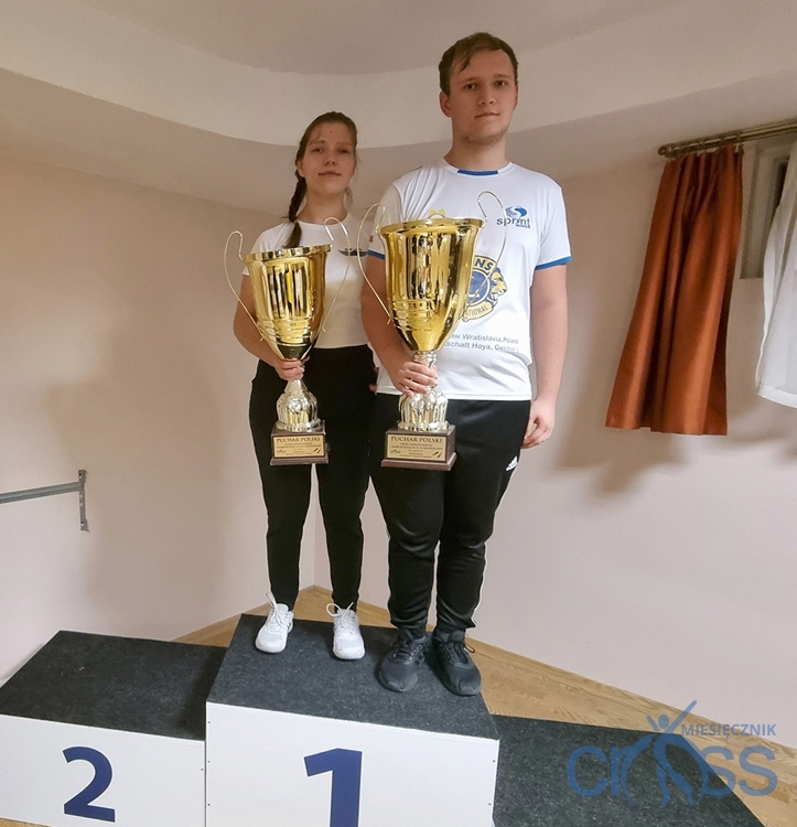 dwie osoby na podium z pucharami