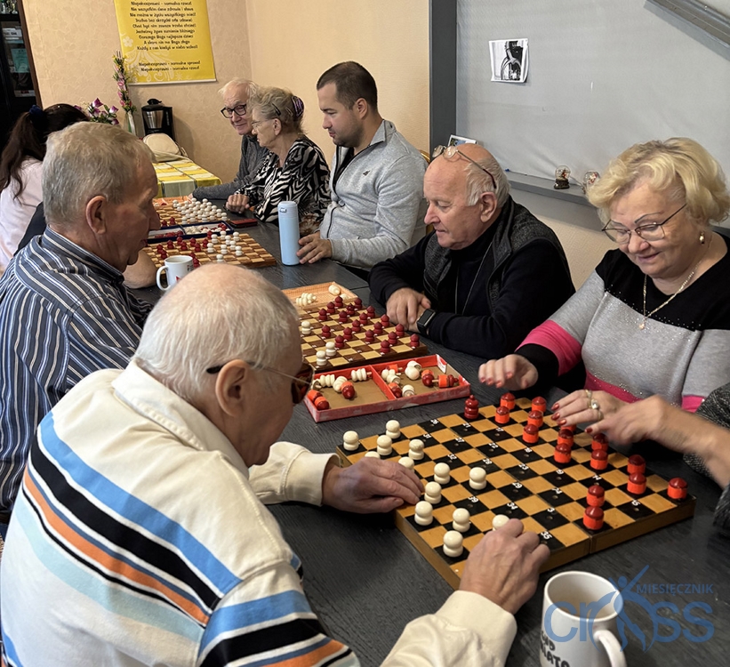 grupa os&oacute;b na sali gra w warcaby