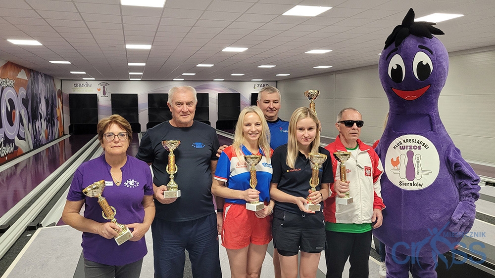 grupa os&oacute;b na podium z pucharami