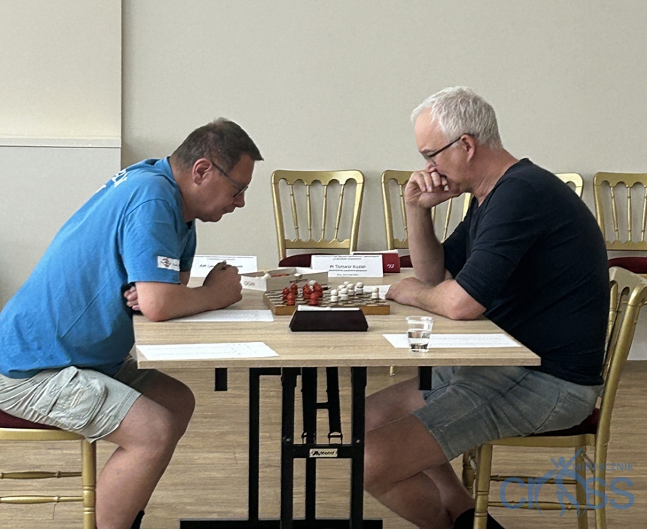 dw&oacute;ch mężczyzn przy stole gra w warcaby